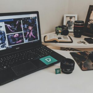 A modern workspace featuring a laptop, photography equipment, and an open book on a desk.